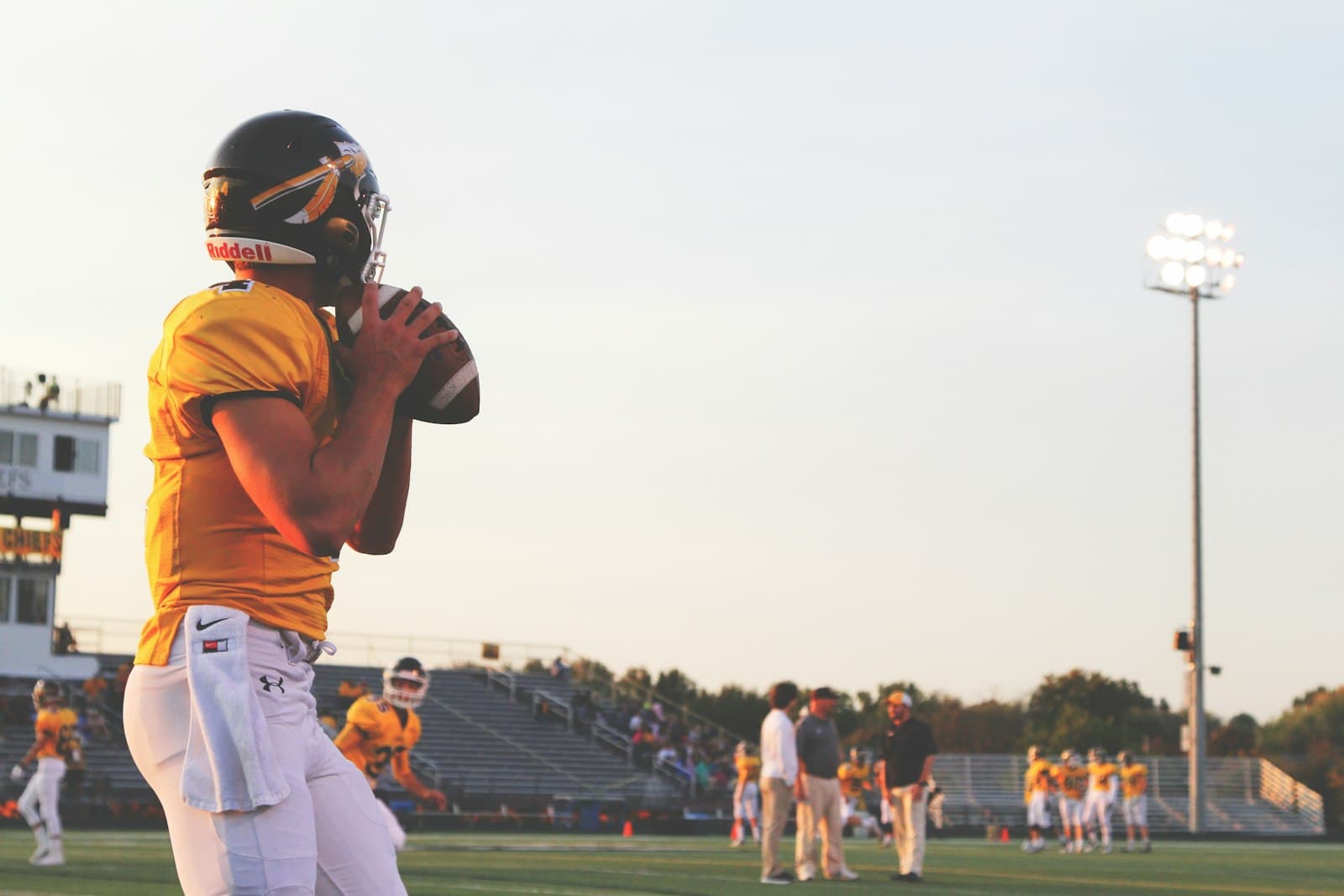 Quarterback in a yellow uniform gripping the football before a throw