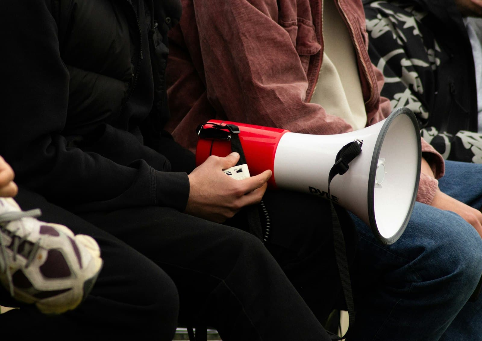 Person holding a red and white megaphone in their lap