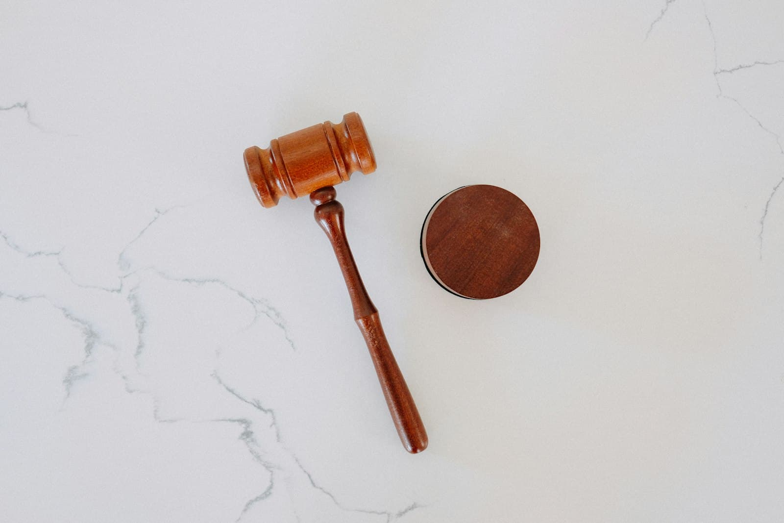 Wooden auction gavel resting beside its sound block on a marble surface
