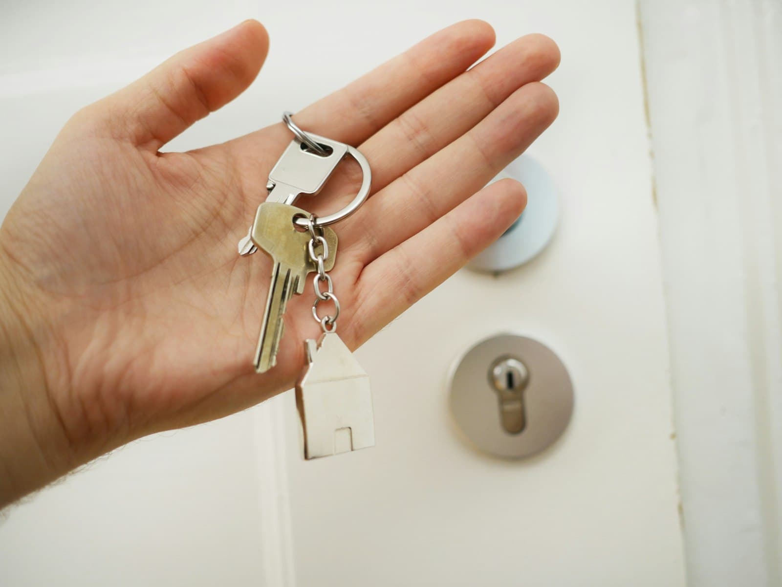 Hand holding a set of keys with a house-shaped keychain