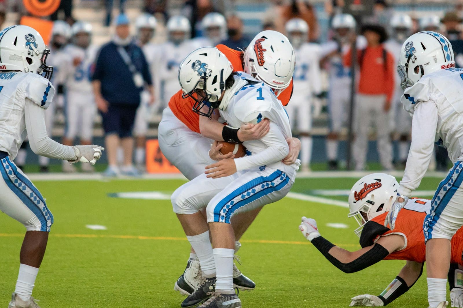 High school football players colliding at the line during a night game