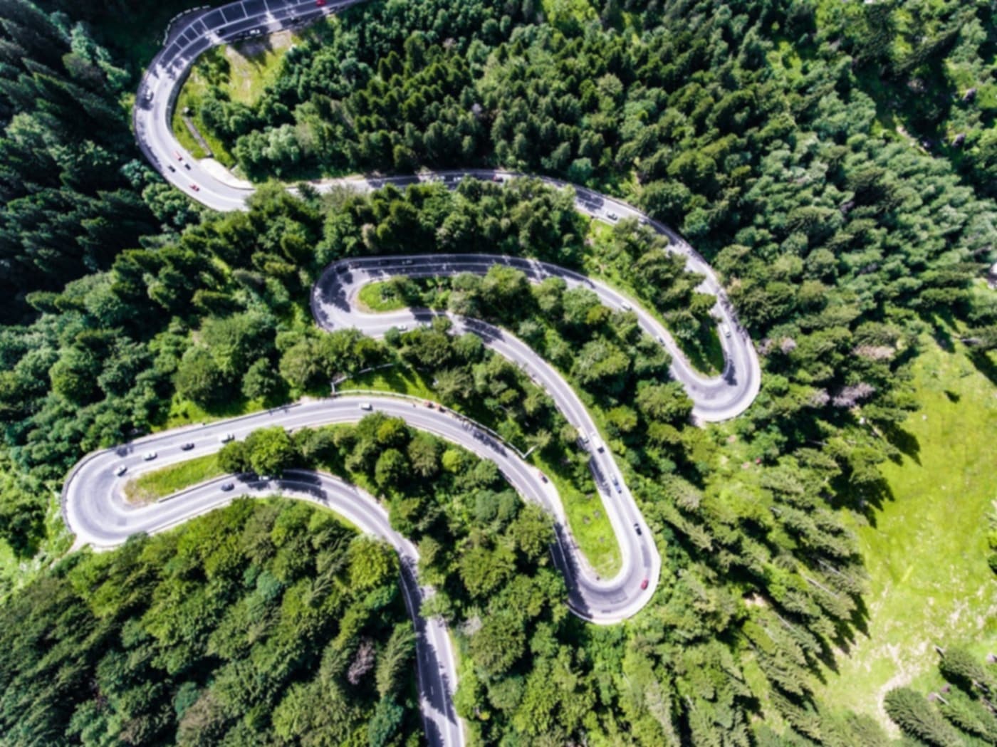 Aerial view of a road snaking through forest in tight switchbacks
