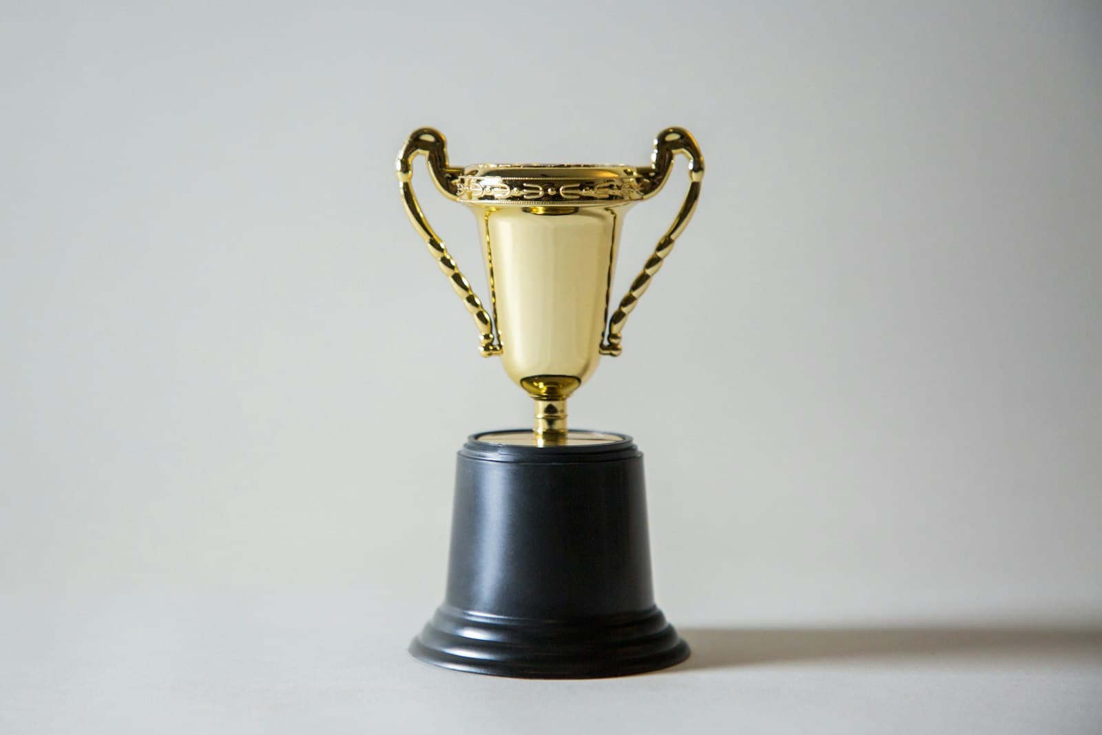 Gold trophy cup on a black base against a plain background
