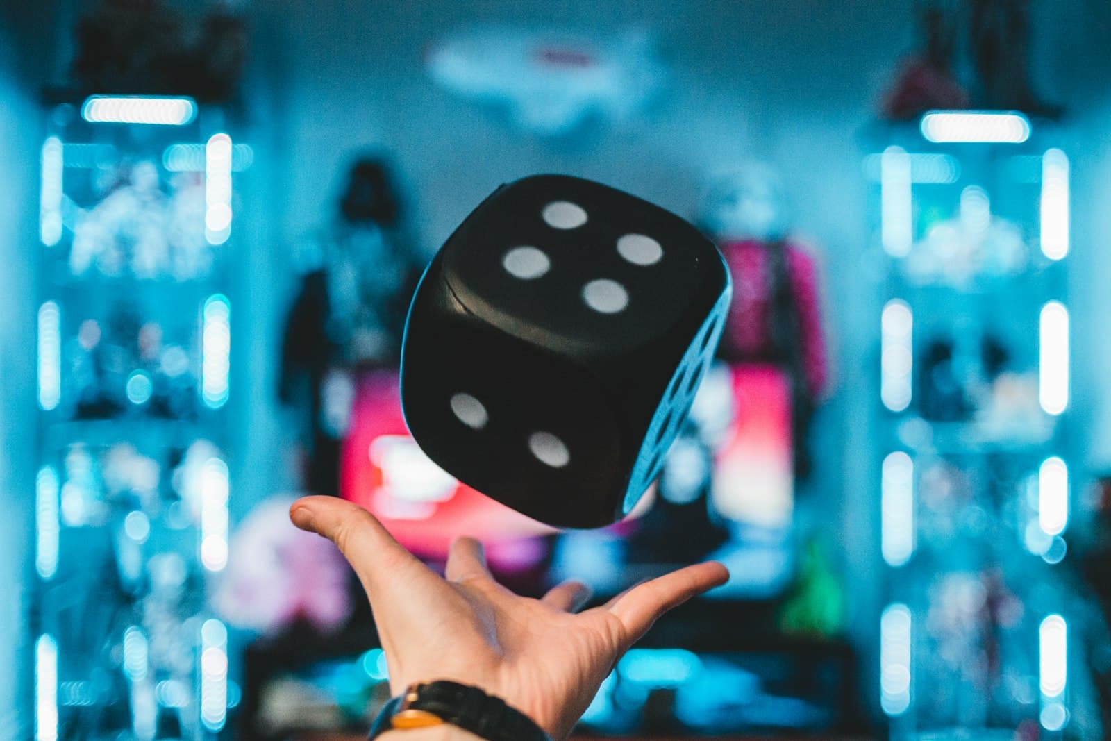 Hand tossing a large black die into the air