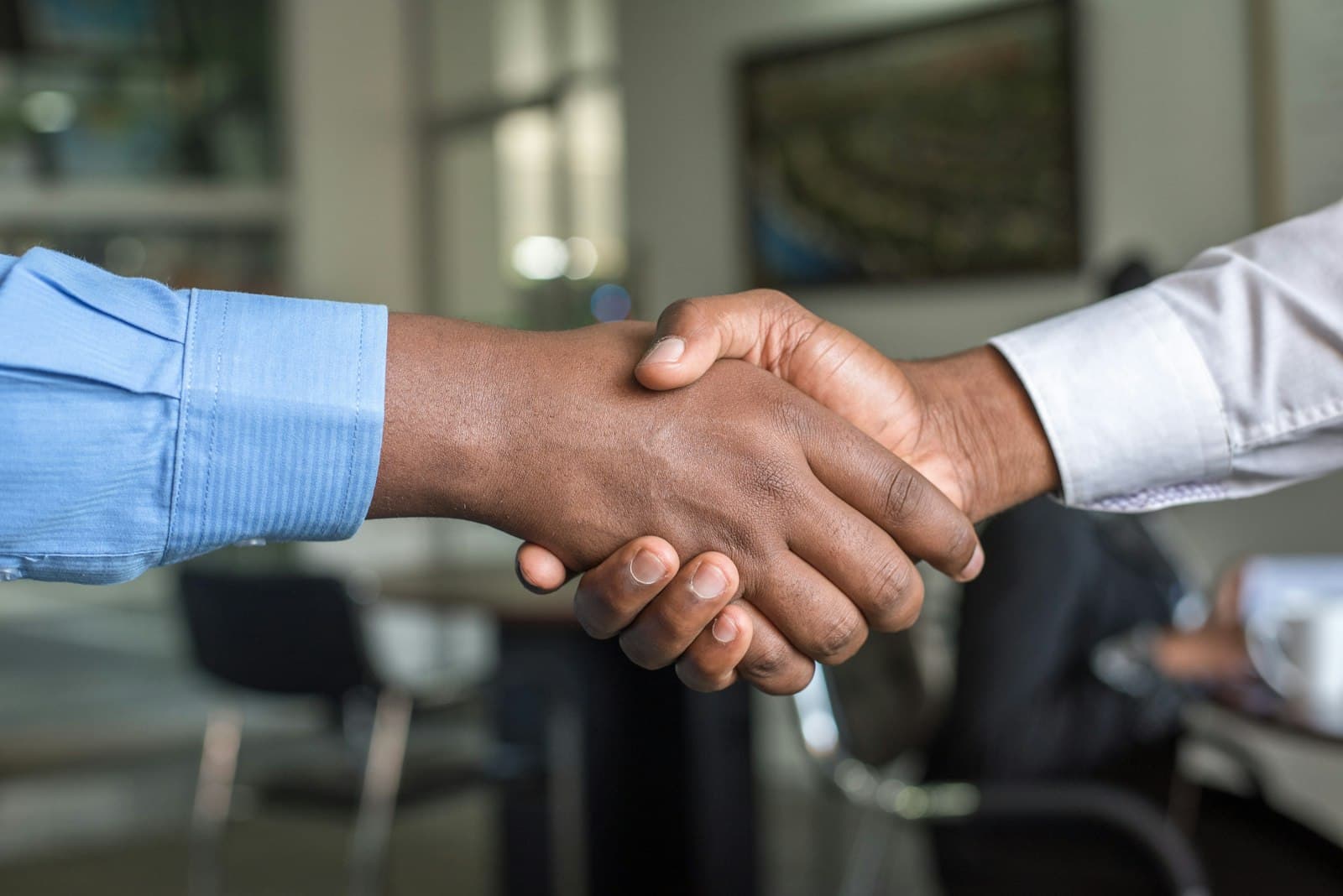 Two people shaking hands across an office table