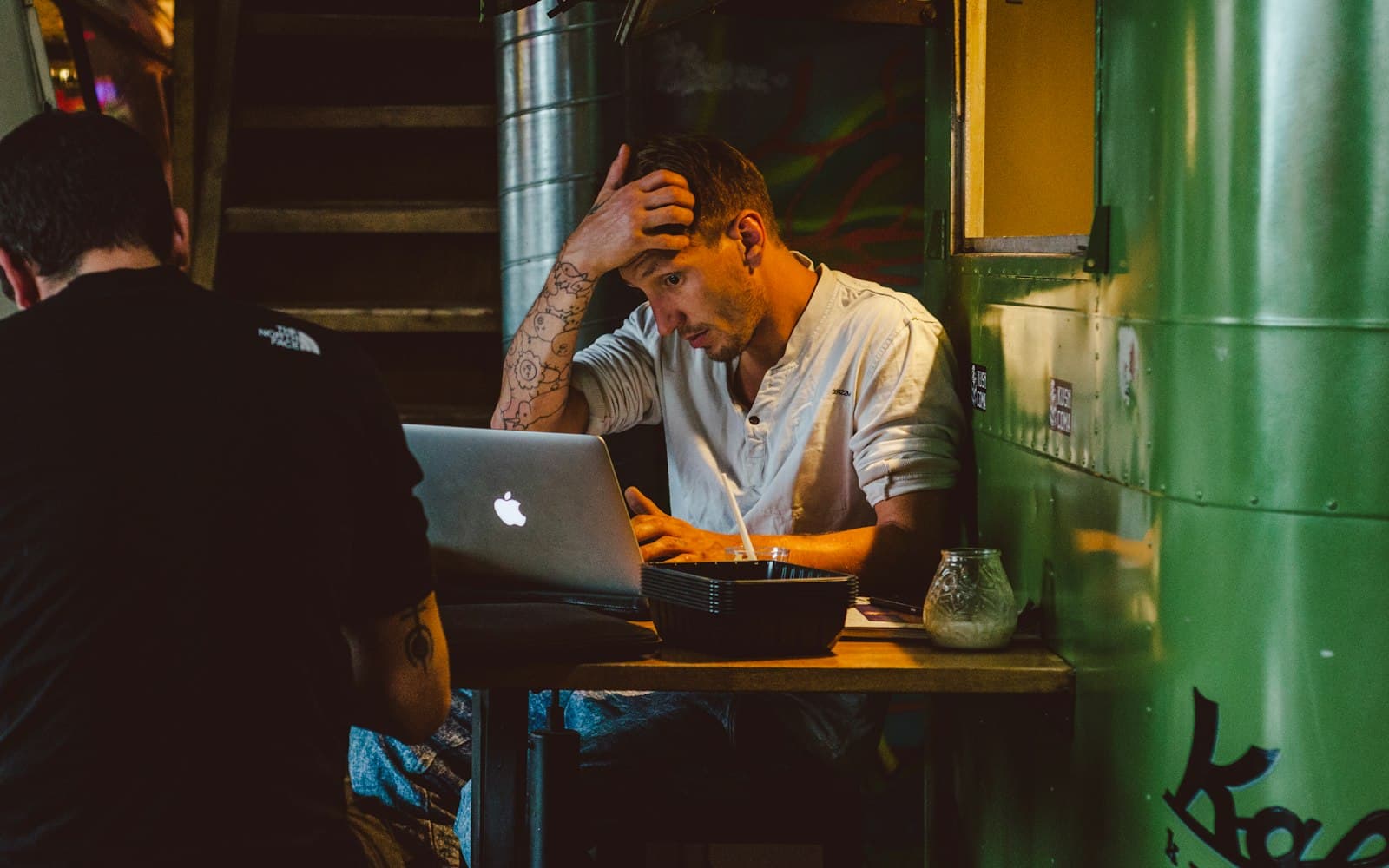 Frustrated man holding his head while staring at a laptop